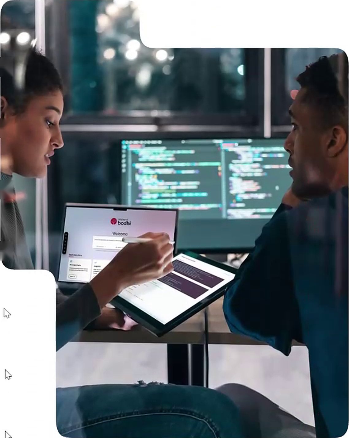 Two colleagues reviewing an application on a tablet in front of screens of code